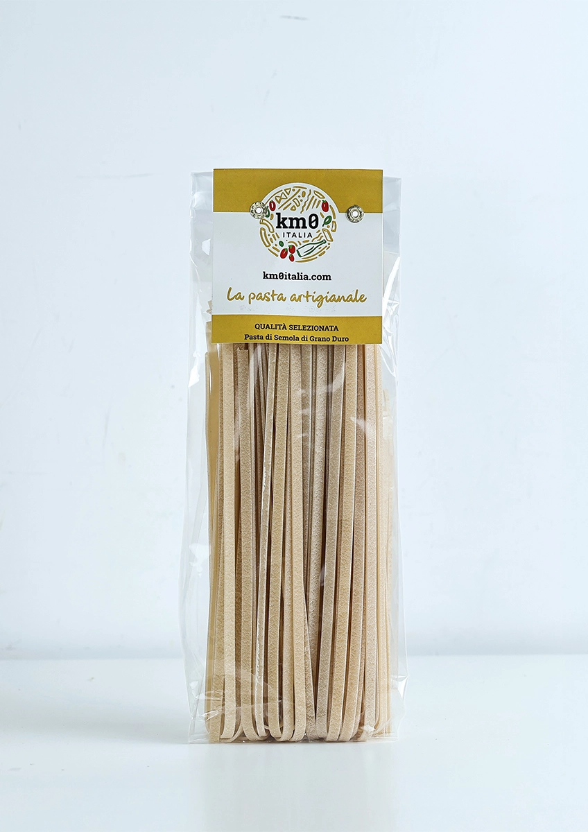 Tagliatelle artigianali Km0italia trafilate al bronzo in primo piano, ideali per ragù e sughi della tradizione italiana.